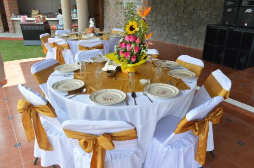 a table set for a wedding with a sunflower centerpiece at Hotel Real Campestre Tepetoci in Tepexi del Río