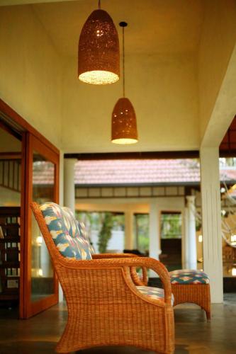 a wicker chair sitting on a porch with two lights at Cranganor History Café & Riverside Château in Parūr