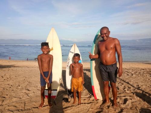 a man and two boys standing on the beach with surfboards at Rock Pool Homestay in Huu