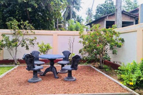 a table and four chairs in a garden at Ran-Weera Villa in Kahawa