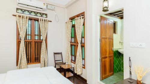 a bedroom with a bed and a chair and a mirror at Kumarakom Wood Castle Serviced Appartments in Kumarakom