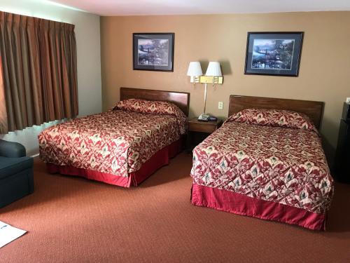 New MartinsvilleにあるTravelers Innのベッド2台とソファが備わるホテルルームです。