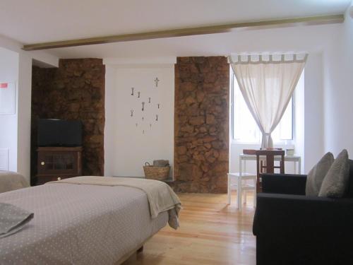 um quarto com uma cama, uma televisão e uma janela em Casa Zé Bonito I em Cascais