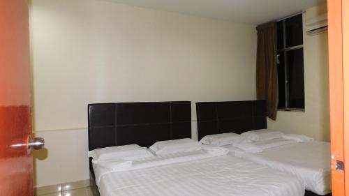 a bedroom with two beds with white sheets at Hotel Ocean in Lahad Datu