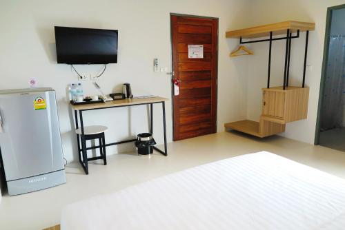 a room with a refrigerator and a table and a television at Phuket Marine Poshtel - SHA Plus in Chalong 