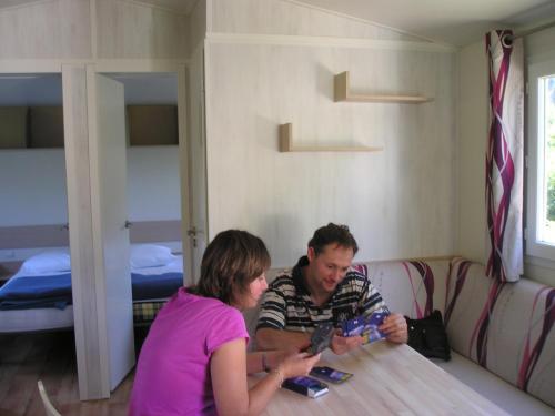 a man and woman sitting at a table with their cell phones at Camping Base de Loisirs du Lac de la Moselotte in Saulxures-sur-Moselotte