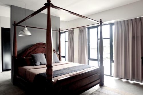 - une chambre avec un lit à baldaquin et une grande fenêtre dans l'établissement Antique Chiangmai, à Chiang Mai