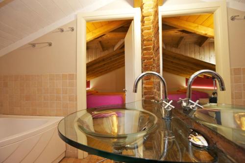 ヴェルバーニアにあるAppartamenti Lungolagoのバスルーム(ガラスの洗面台、バスタブ付)