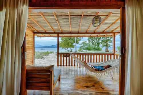 a hammock in a room with a view of the ocean at Kuda Laut Boutique Dive Resort in Bunaken