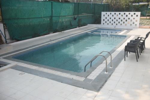 a large swimming pool with chairs and a fence at Athi Resorts in Bogmolo