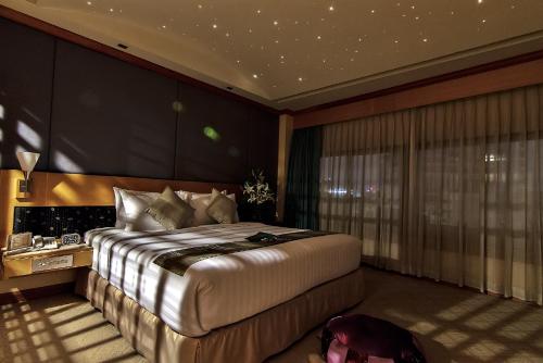 a bedroom with a large bed and a large window at Bossotel Bangkok in Bangkok