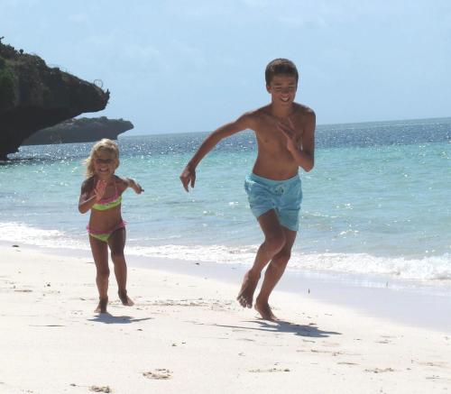 a man and a little girl running on the beach at Baobab Village in Watamu