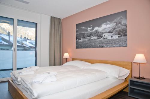 ein Schlafzimmer mit einem großen Bett und einem großen Fenster in der Unterkunft Apartment Narzisse - GriwaRent AG in Interlaken