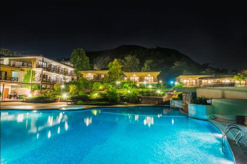 una grande piscina notturna con edifici di Upper Deck Resort a Lonavala