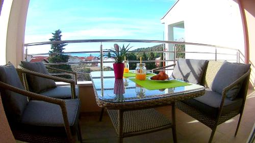 una mesa y sillas en un balcón con vistas al océano en Apartments Tea en Podaca