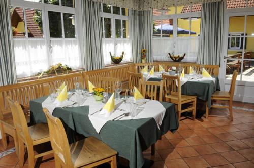 a dining room with tables and chairs and windows at Landhof Steinbäck in Sankt Stefan ob Stainz