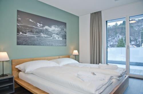 Schlafzimmer mit einem großen weißen Bett und einem Fenster in der Unterkunft Apartment Krokus - GriwaRent AG in Interlaken