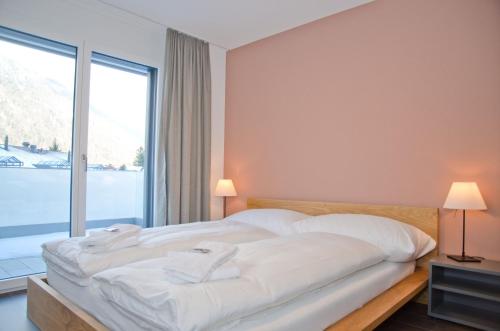 a bedroom with a large bed and a large window at Apartment Anemone - GriwaRent AG in Interlaken