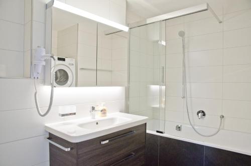 y baño blanco con lavabo y ducha. en Apartment Anemone - GriwaRent AG, en Interlaken
