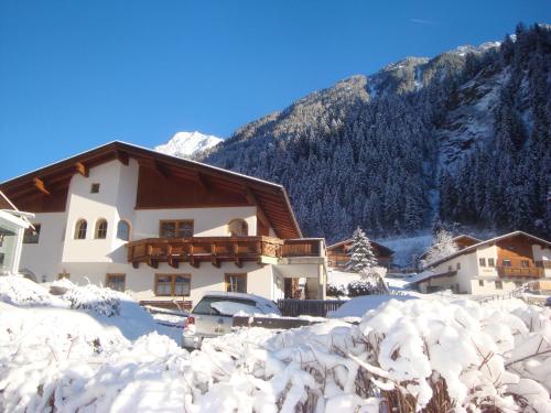 a house in the snow with mountains in the background at Alpenhaus Christian in Neustift im Stubaital