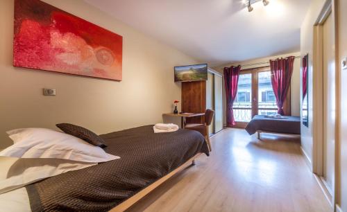 a bedroom with a bed and a chair and a window at Hotel Rhodos Morzine in Morzine