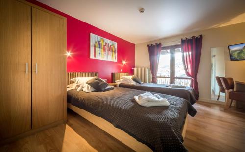 two beds in a room with red walls at Hotel Rhodos Morzine in Morzine
