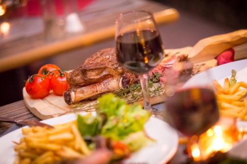 a table with a plate of food and a glass of wine at Hotel Rhodos Morzine in Morzine