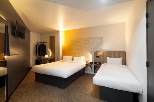 a hotel room with two beds with white sheets at B&B HOTEL NANTERRE Rueil-Malmaison in Nanterre