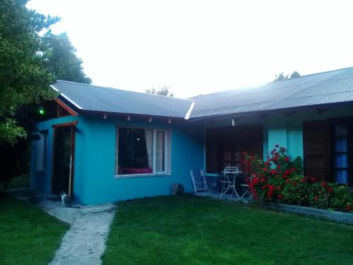 a blue house with a lawn in front of it at La Estacion Hostel in Lago Puelo