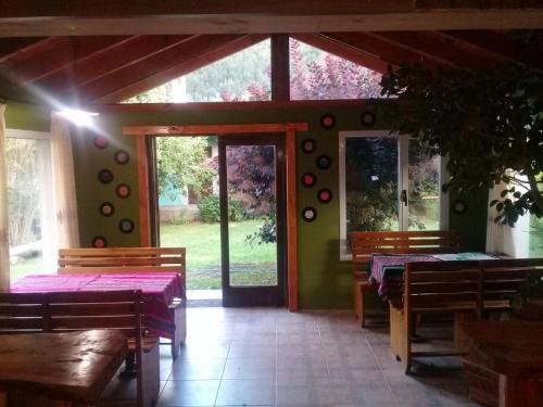 a dining room with tables and chairs and glass doors at La Estacion Hostel in Lago Puelo