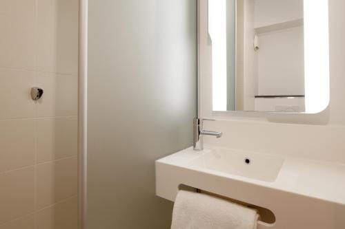 Baño blanco con lavabo y espejo en B&B HOTEL NANTERRE Rueil-Malmaison en Nanterre