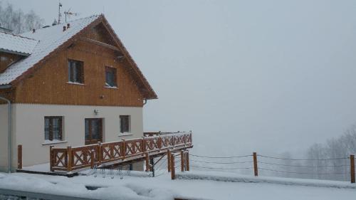 a house with a wooden deck in the snow at Uroczysko starych sztolni in Szklarska Poręba