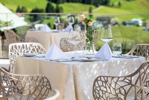 a white table with glasses and a vase with flowers at Haller's Geniesserhotel in Mittelberg