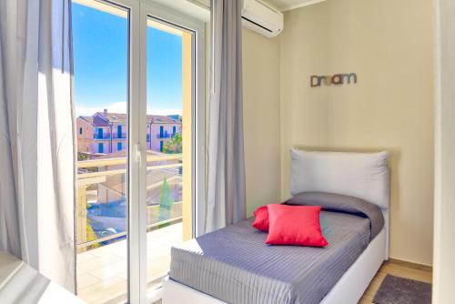 ディアーノ・マリーナにあるColibrì Apartments Diano Marinaの窓付きの部屋で、ベッド1台(赤い枕付)