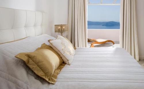 a bedroom with a white bed with a window at Gold Suites - Small Luxury Hotels of the World in Imerovigli