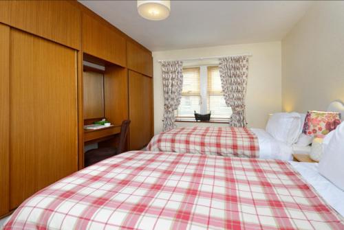 a bedroom with a red and white plaid bed at Granny’s Cottage in Newcastleton