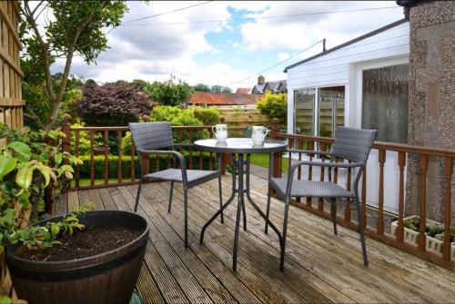 eine Terrasse mit 2 Stühlen und einem Tisch auf einer Terrasse in der Unterkunft Granny’s Cottage in Newcastleton