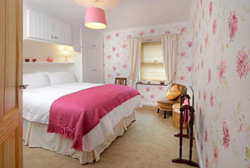 a bedroom with a bed with pink floral wallpaper at Granny’s Cottage in Newcastleton