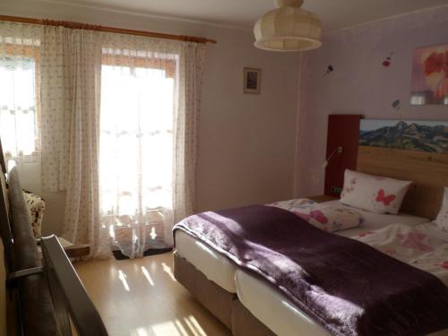 a bedroom with a bed and two windows at Berggasthaus Kraxenberger in Brannenburg