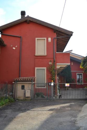 czerwony dom z płotem przed nim w obiekcie B&B Casa Mia w mieście Desenzano del Garda
