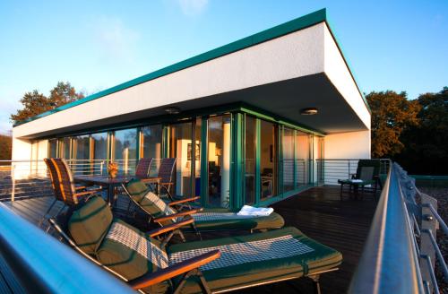 a house with a deck with chairs and a table at Parkhotel IV Jahreszeiten Kühlungsborn in Kühlungsborn