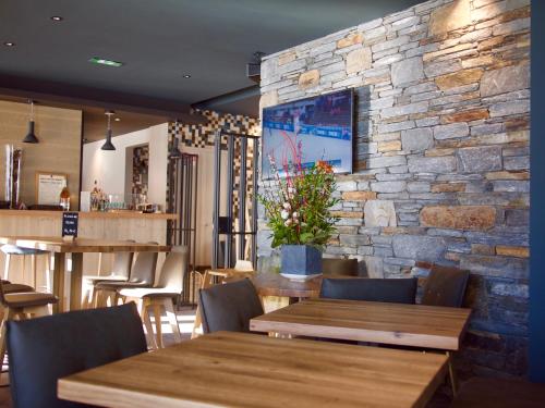 un restaurant avec des tables et des chaises en bois et un mur en pierre dans l'établissement Alberta Hotel & Spa, à Val Thorens