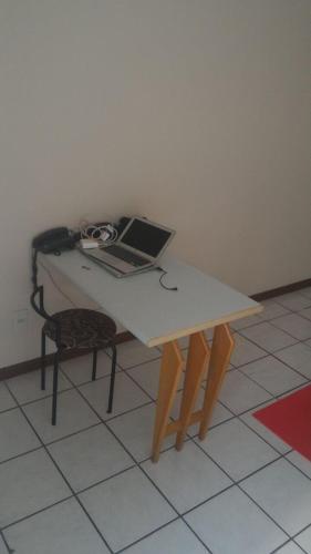 a laptop computer sitting on a table with a chair at Apart Hotel Quartier Latin in Vitória