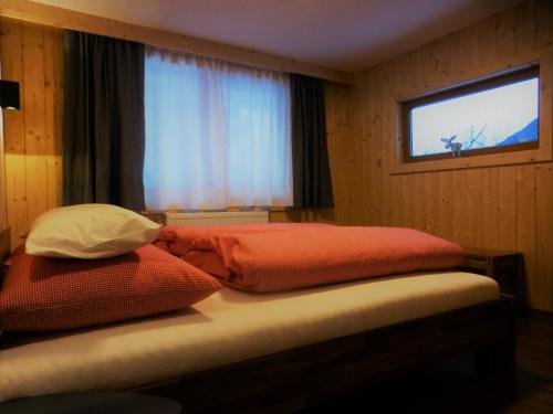 1 cama con 2 almohadas en una habitación con ventana en Chalet Auszeit, en Arzl im Pitztal