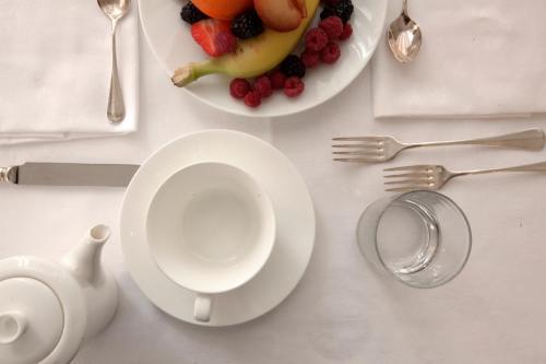 a white table with a plate of fruit and a tea pot at Hotel Grand'Italia in Padova