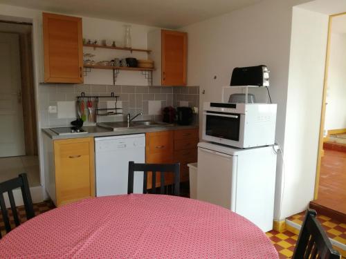a kitchen with a white refrigerator and a table with chairs at Ma Petite Maison Chambourgeoise in Chambourg-sur-Indre
