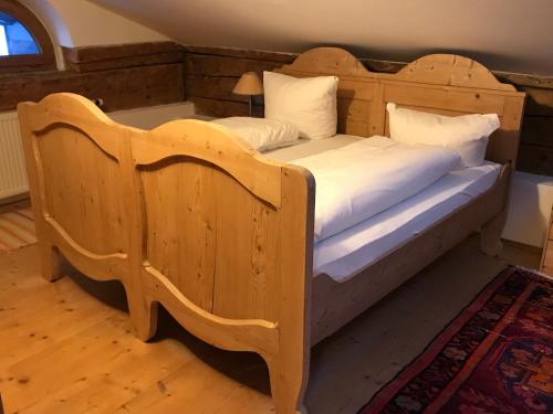 a wooden bed with white sheets and pillows at Posthotel Sachrang in Sachrang