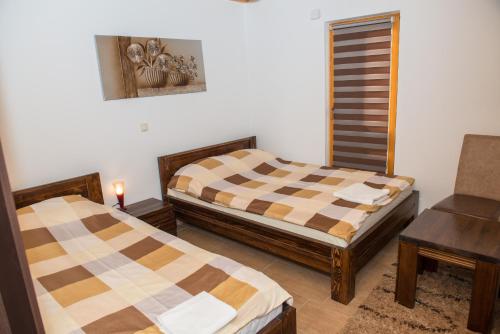 two beds in a room with a table and a chair at Motel Orhideja in Donji Vakuf