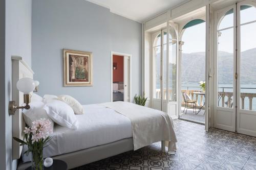 a white bedroom with a bed and a balcony at Villa Maria Hotel in Cannobio