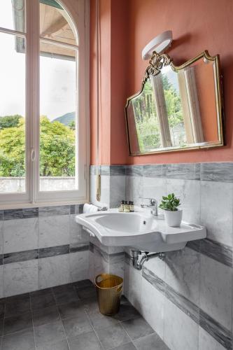 a bathroom with a sink and a mirror and a window at Villa Maria Boutique Hotel in Cannobio